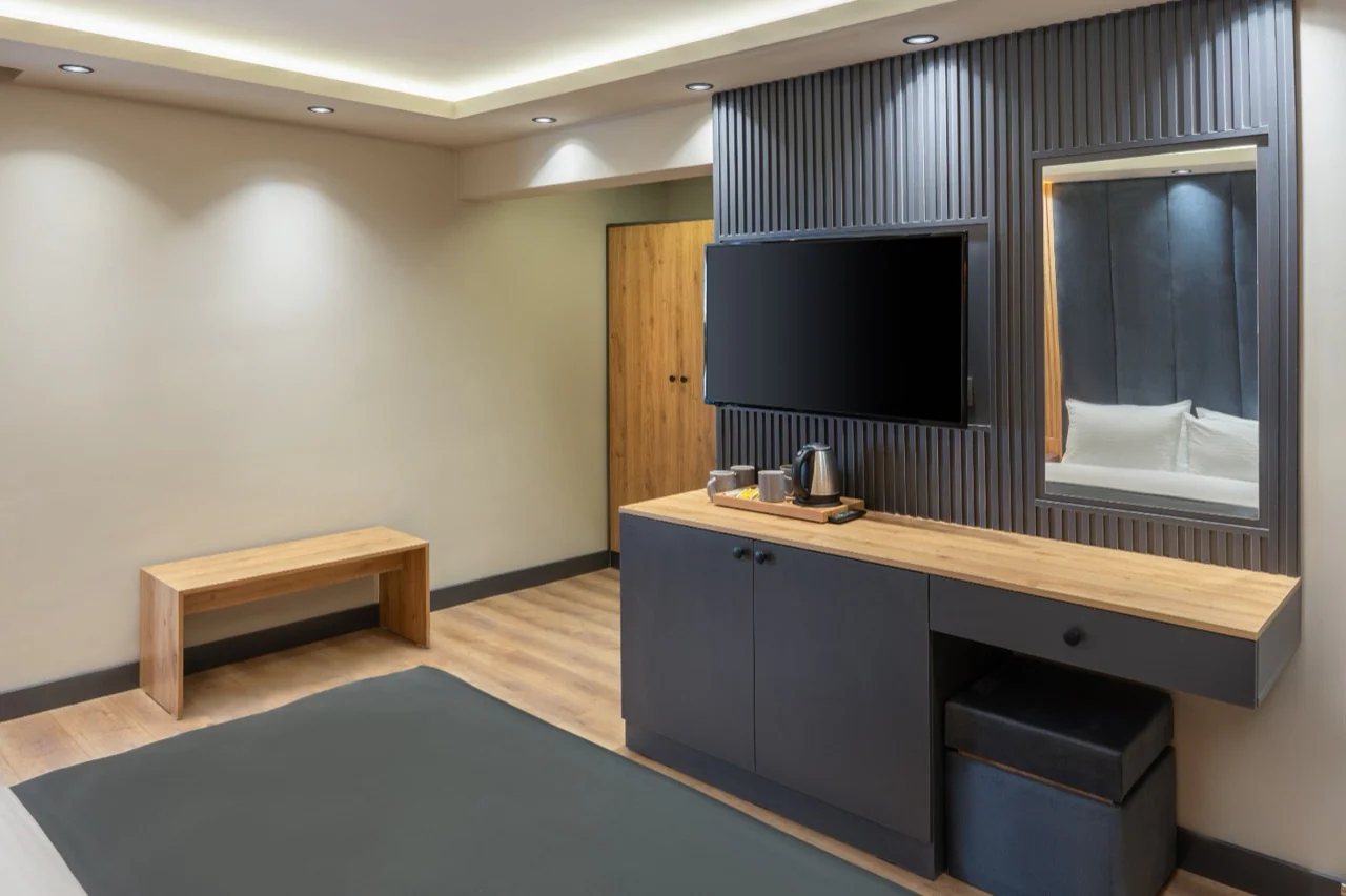 Yeşilton Hotel odasında televizyon, çalışma yüzeyi ve ikram ünitesi